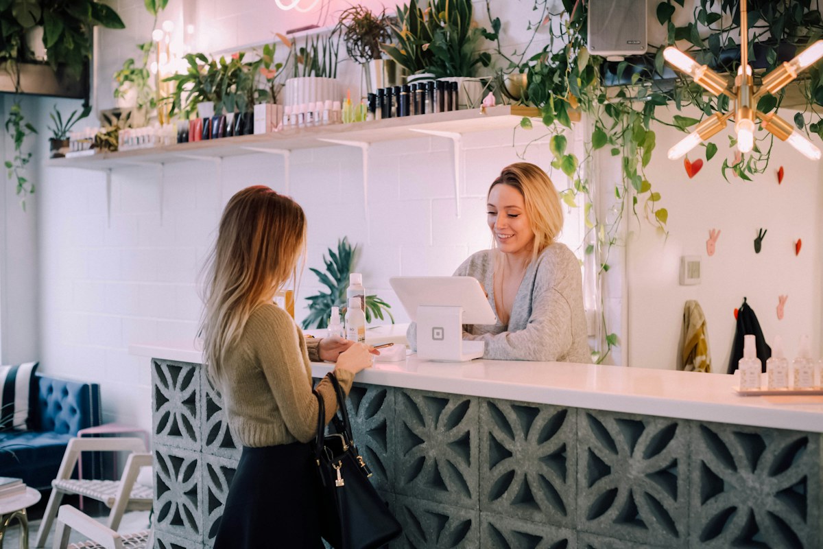 Commerciante serve una cliente al banco del suo negozio